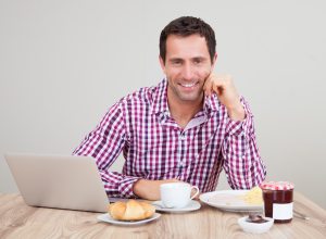 Portrait Of Young Man Using Laptop At Breakfast